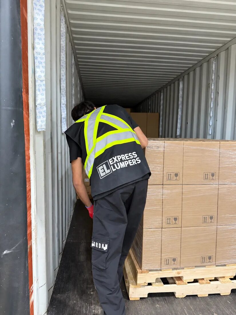 Express Lumpers associate unloading palletized freight from a shipping container in Alberta