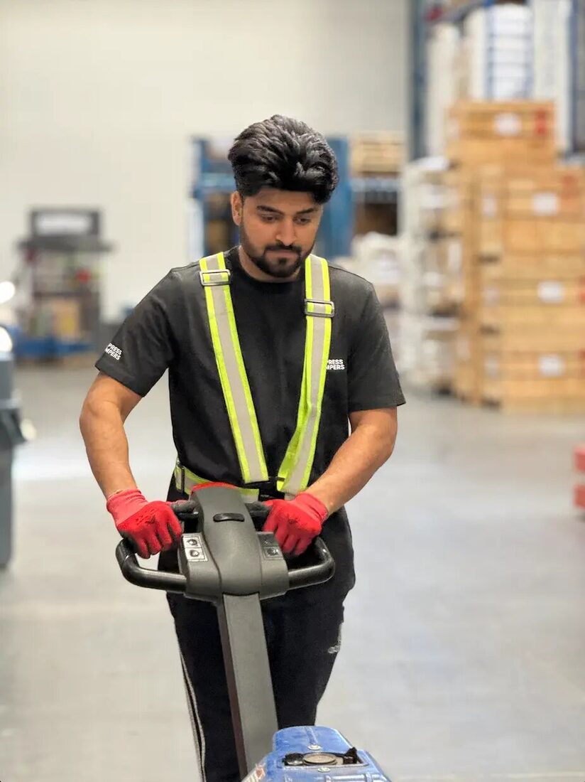Express Lumpers material-handling operator using a powered pallet jack in an Alberta warehouse