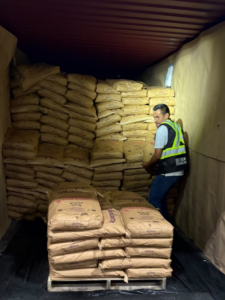 Express Lumpers associate manually unloading bulk sacks from a floor-loaded shipping container in Renton