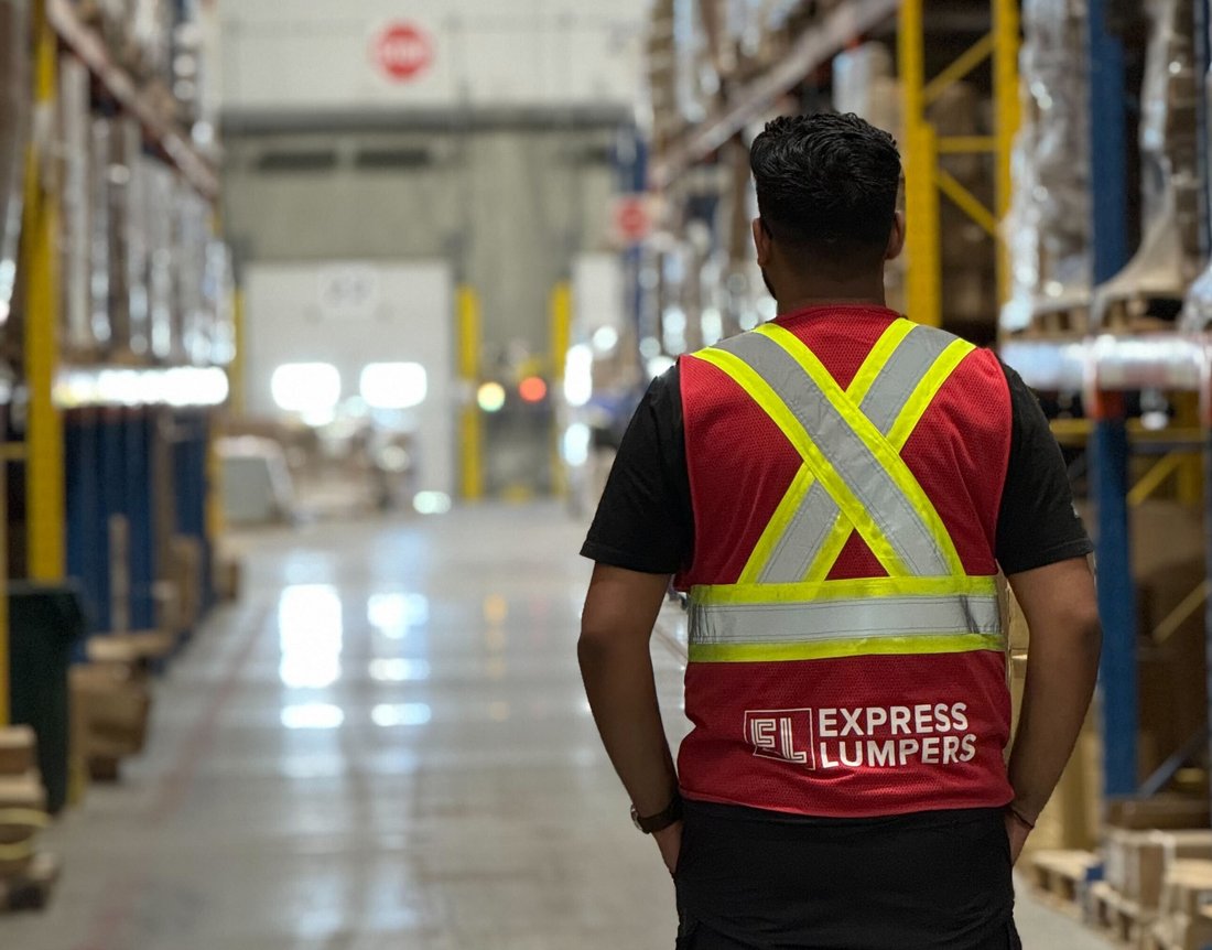 Express Lumpers associate in an Express Lumpers vest walking a Renton warehouse aisle