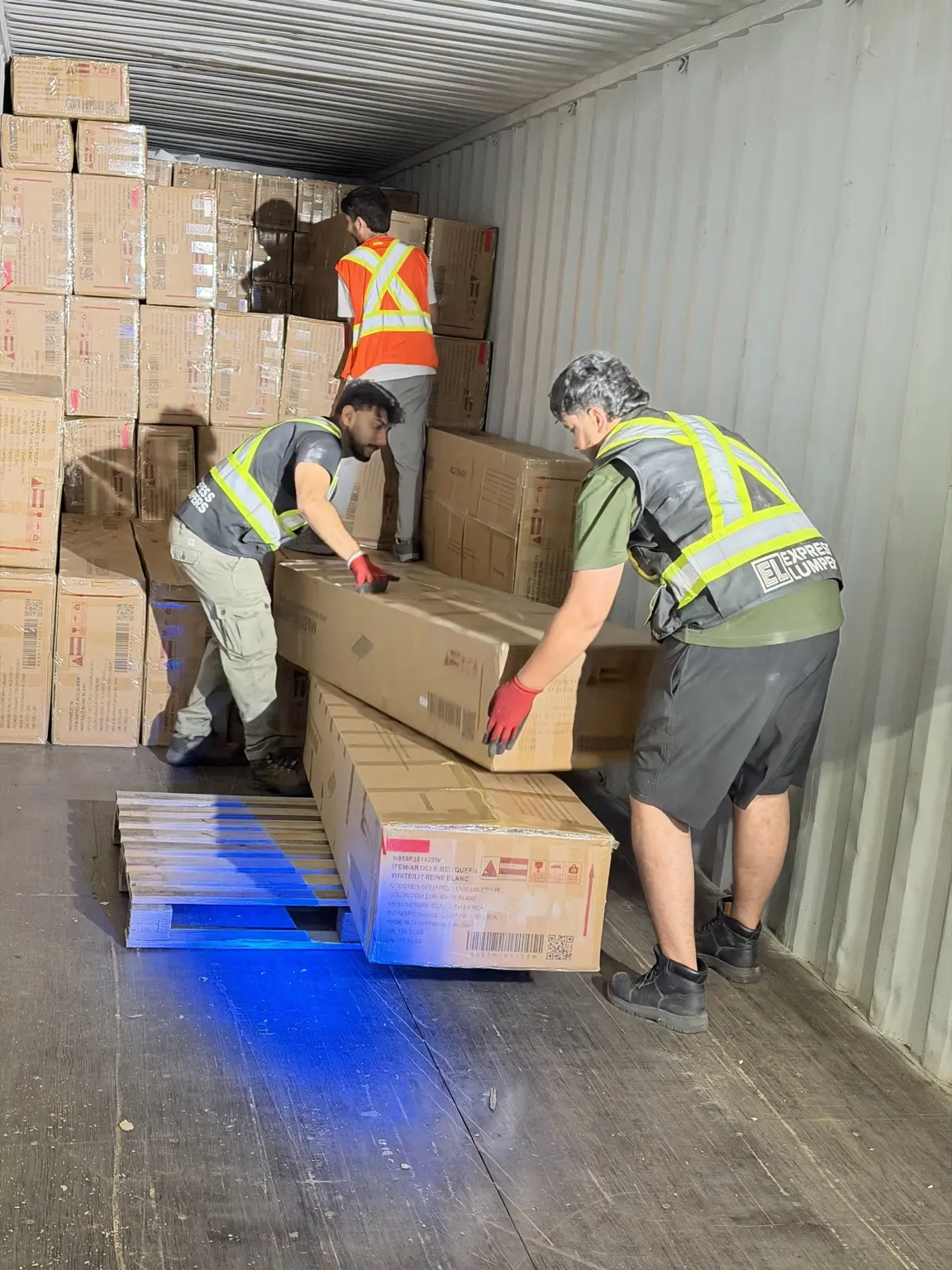 Express Lumpers crew unloading large cartons from a shipping container in Ontario